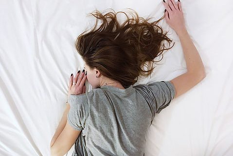 Woman sleeping facedown on a bed.