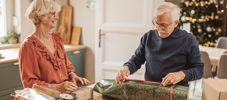 Couple wrapping holiday gifts at a table with good posture to prevent neck and back pain